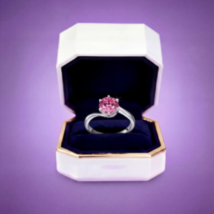 Pink moissanite engagement ring displayed in an Amethyst jewelry box with velvet interior.